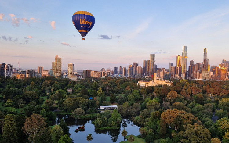 Hot air balloons drifting over the Melbourne city skyline at dawn